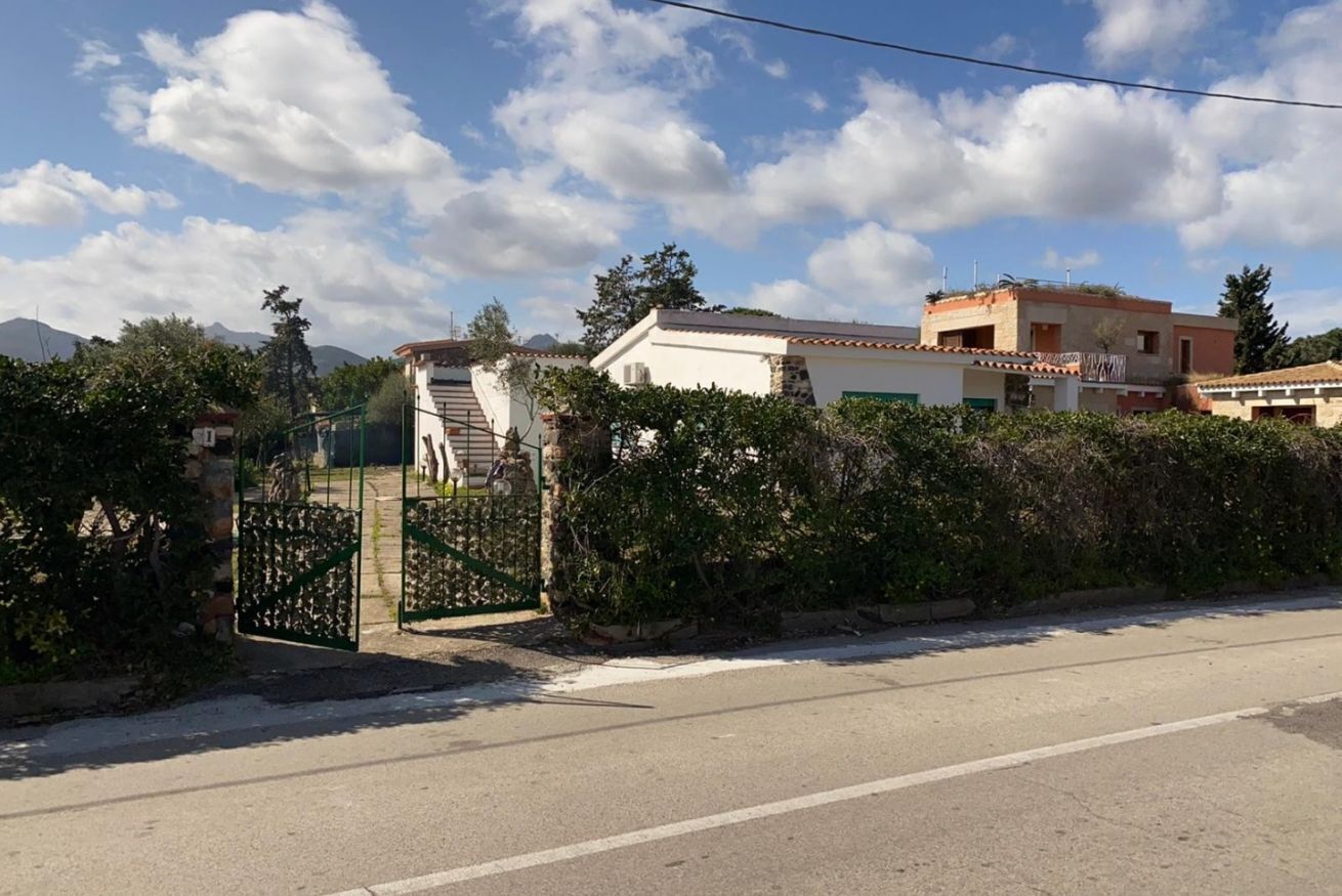 A residential area with a gated entrance, a staircase leading to a house, and a mountain in the background.