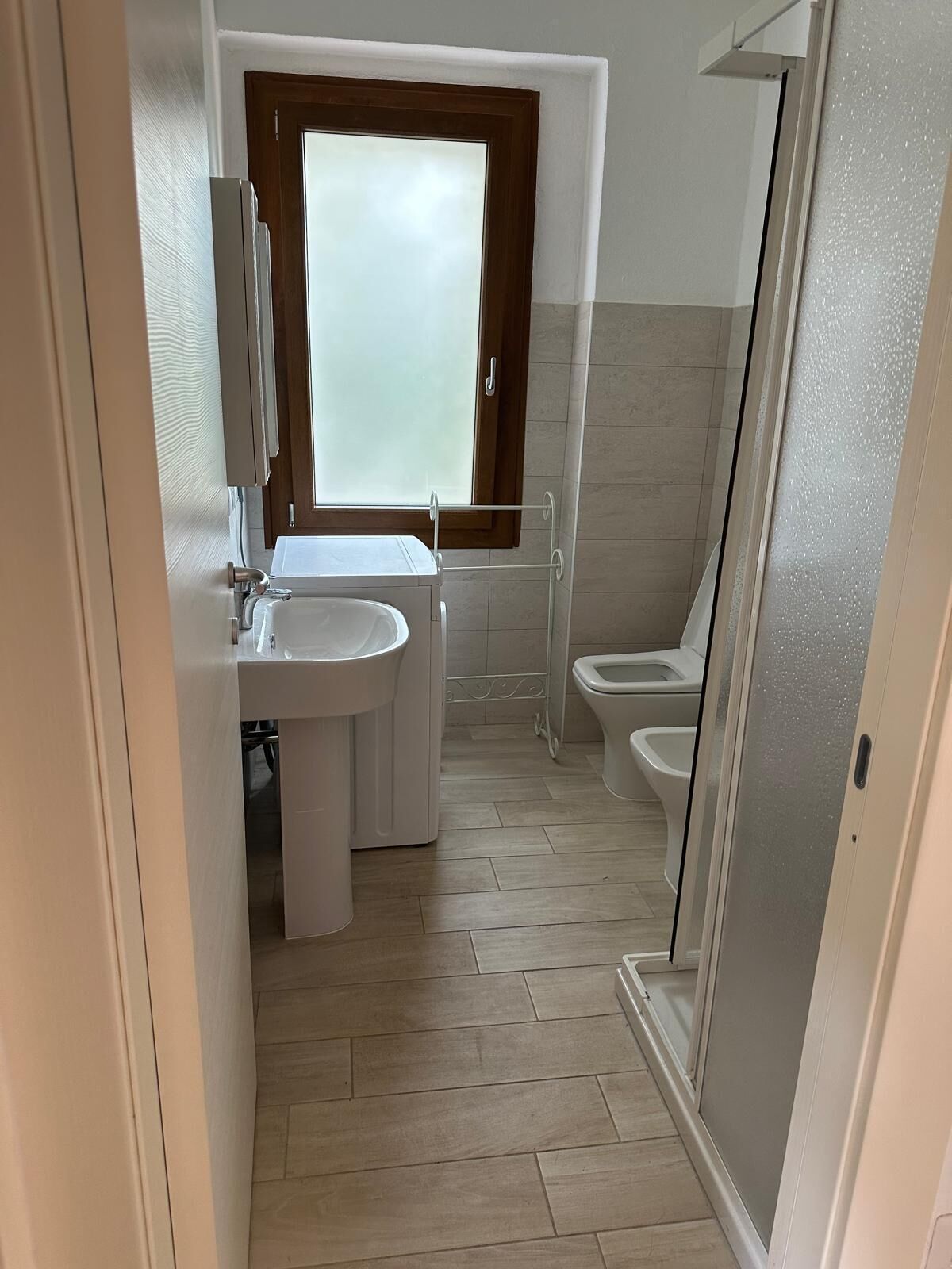 A compact bathroom with a sink, toilet, and shower area.
