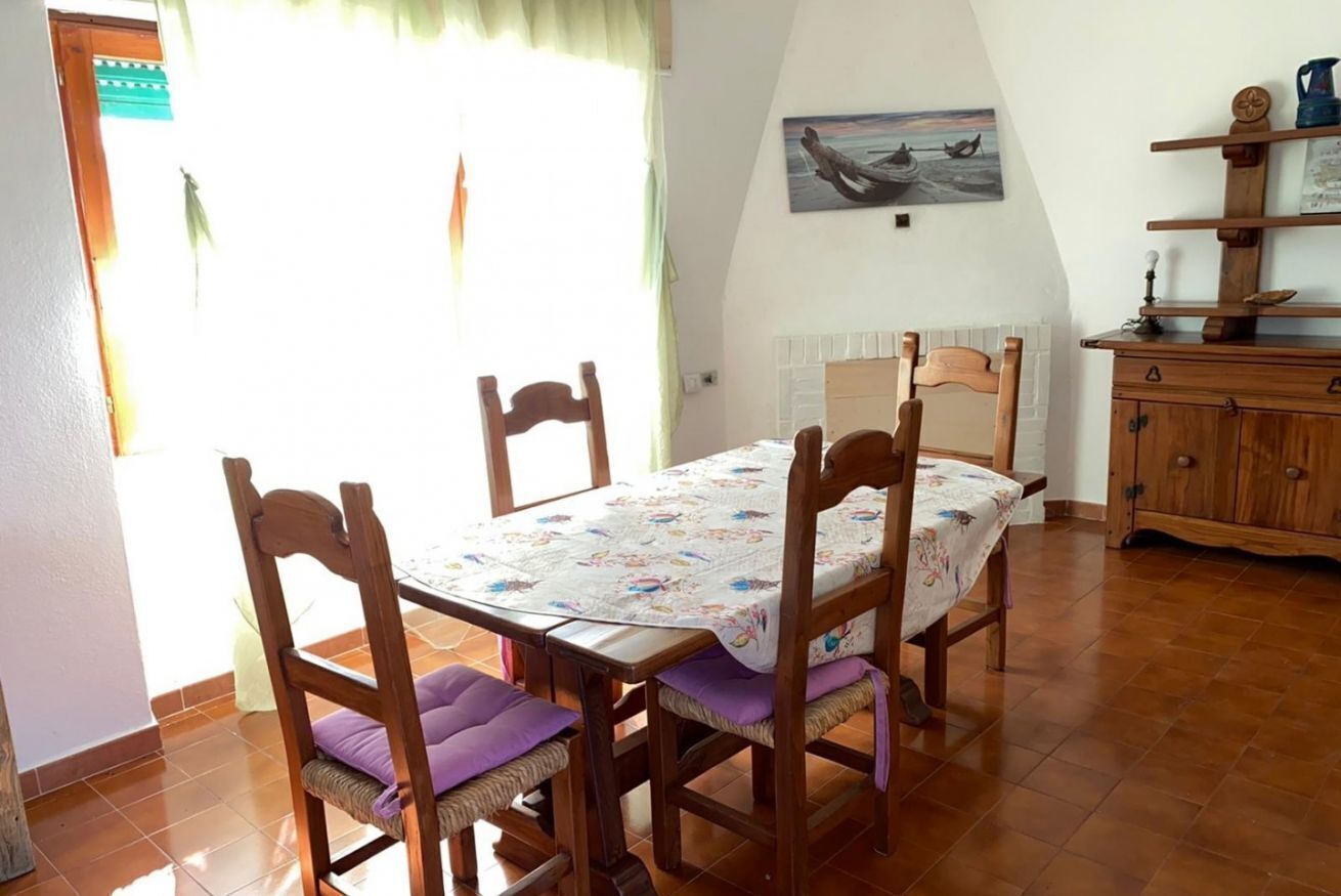 Un coin repas avec une table et des chaises en bois, un tableau accroché au mur et un buffet en bois.