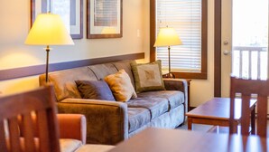 A living room with a sofa, two lamps, a table, and chairs. - 2 Bedrooms | Mountain Views l AC (Fernie)