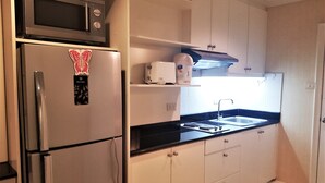 Una cocina compacta equipada con microondas, refrigerador, tostadora y pileta.