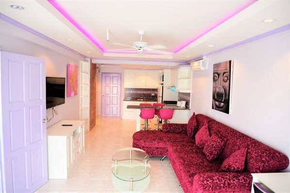 Relax in this stylish living space with a plush sofa, glass coffee table, and modern kitchen.