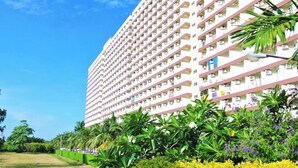 A high-rise hotel with multiple balconies, surrounded by lush greenery and a well-maintained lawn. - Sea View Apartment Jomtien Beach Condominium S2 16th Floor Pattaya (Pattaya)
