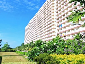 A high-rise hotel with multiple balconies and a well-maintained garden area.