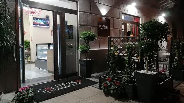 The entrance of a hotel with a modern design, featuring a black entrance mat with the hotel's name, a reception desk, and potted plants. - 55 Aira (Palermo)