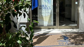 The entrance of AIRA Hotels with a banner displaying the logo and name, a flag, and a security camera. - 55 Aira (Palermo)