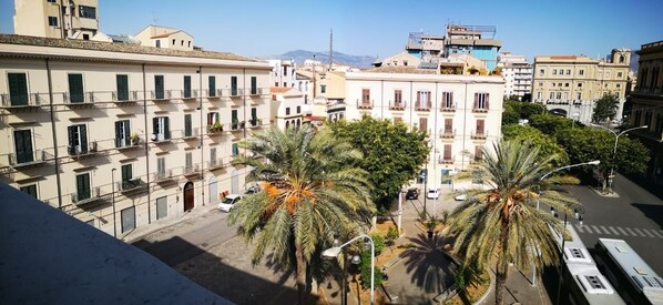 Un immeuble à plusieurs étages doté de balcons, de palmiers et de voitures garées.