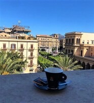 Una vista sulla città con edifici, cielo sereno e una tazza su un tavolo.