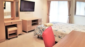 A hotel room with a bed, a desk, a chair, a television, and a wardrobe. - Room-sea View Apartment Jomtien Beach co (Pattaya)
