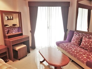 A room with a sofa, a small table, a mirror, and a window with curtains. - Sea View Studio Apartment Jomtien Beach Condominium 11th Floor (Pattaya)