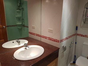Um banheiro com duas pias, chuveiro e vaso sanitário.