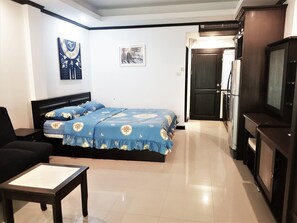 Cozy retreat with a single bed, armchair, and flat-screen TV.
