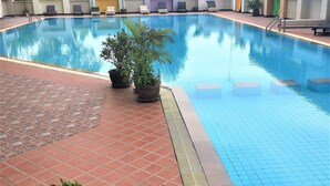 A swimming pool with tiled edges, potted plants, and lounge chairs. - Angket Condominium Fully Furnished 14th Floor Studio Apartment (Pattaya)
