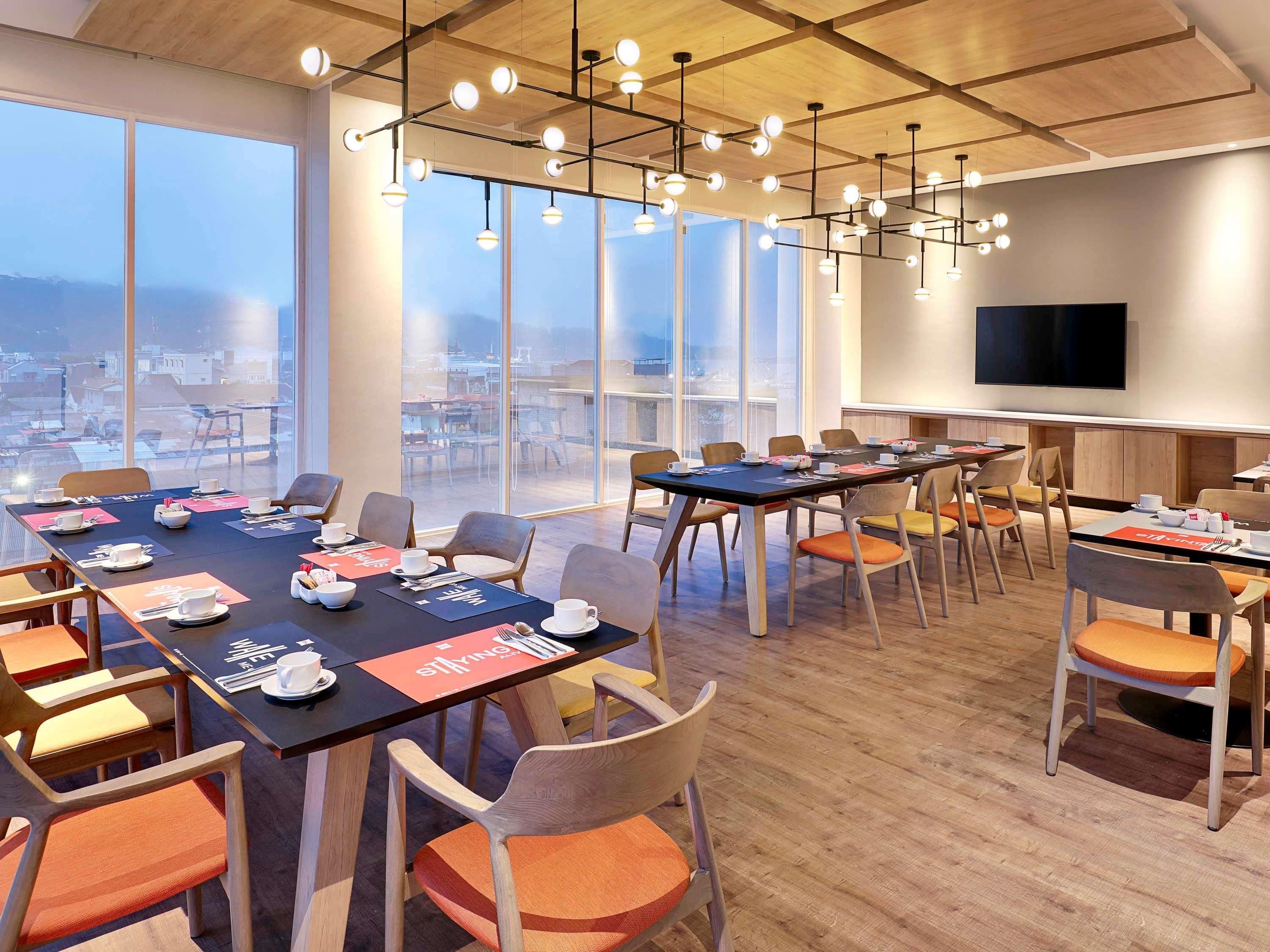A modern conference room with large windows, a flat-screen TV, and a wooden ceiling.