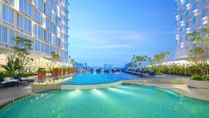 A swimming pool with lounge chairs and potted plants, surrounded by high-rise hotel buildings. - Ibis Samarinda (Samarinda)