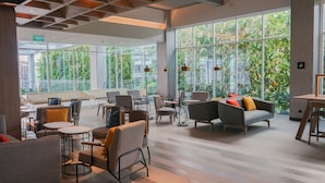 A spacious indoor area with large windows, modern furniture, and a visible exit sign. - Ibis Samarinda (Samarinda)