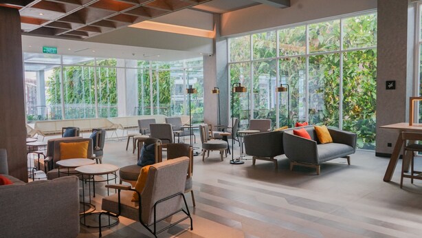 A spacious indoor area with large windows, modern furniture, and a visible exit sign. - Ibis Samarinda (Samarinda)