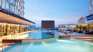 A rooftop pool area with lounge chairs and a bar, surrounded by modern buildings. - Ibis Samarinda (Samarinda)