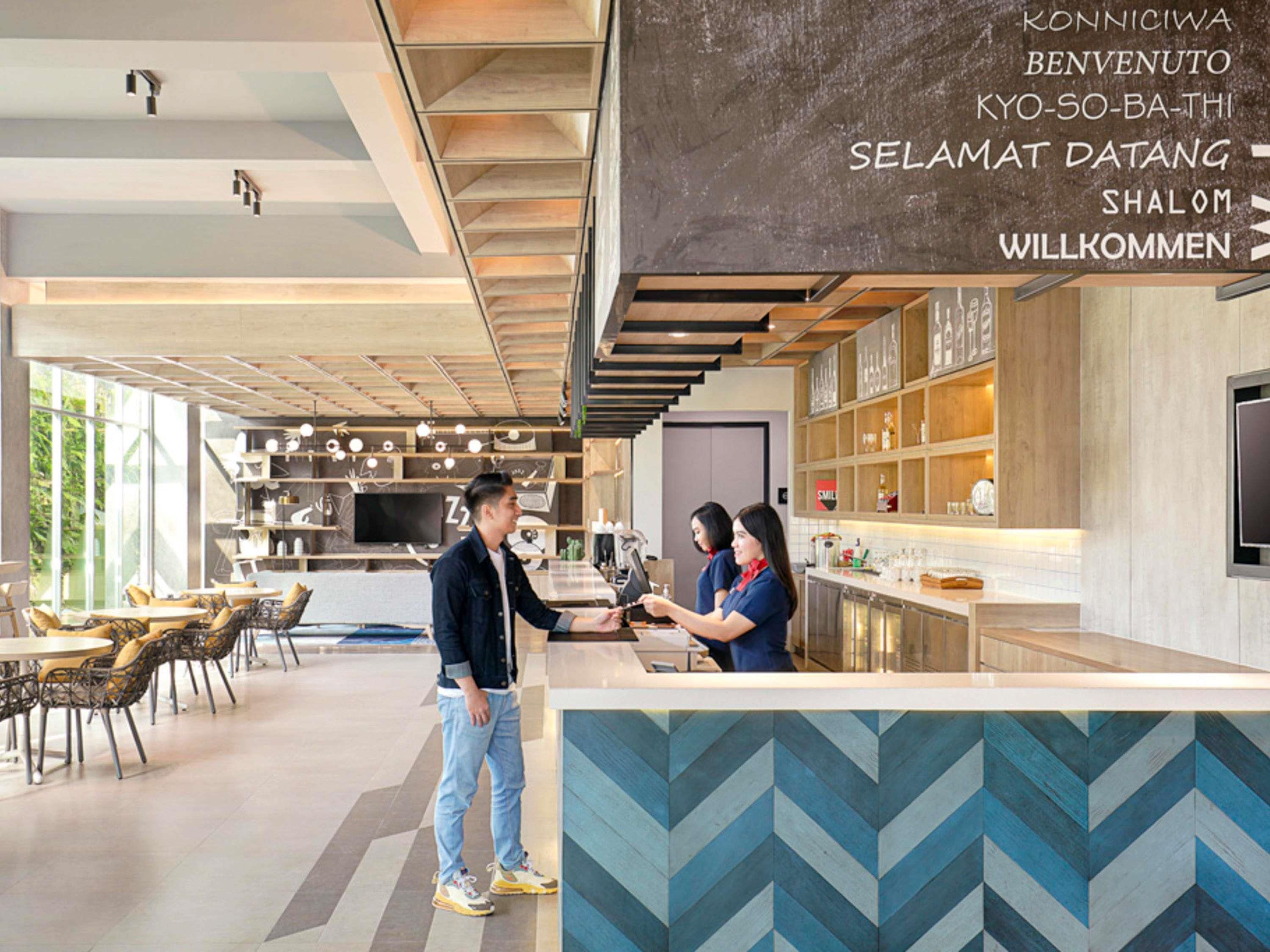 A modern interior with a reception desk, seating area, and kitchen.