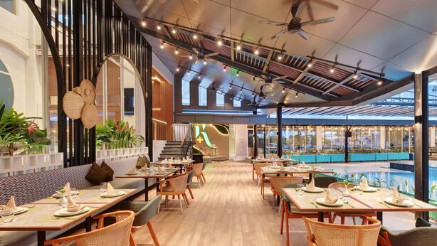 A modern restaurant with wooden flooring, high ceilings, and a pool area visible through large windows. - Ibis Samarinda (Samarinda)
