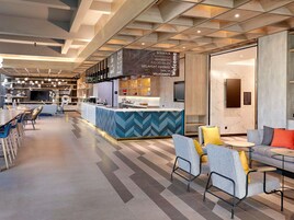 Un moderno vestíbulo de hotel con una recepción, zona de estar y un bar.
