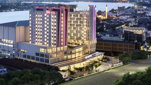 A hotel with multiple floors, a city center sign, and a view of a body of water with distant mountains. - Ibis Samarinda (Samarinda)