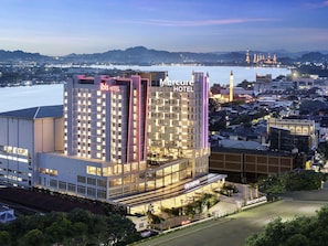 A hotel with multiple floors, a city center sign, and a view of a body of water with distant mountains. - Ibis Samarinda (Samarinda)