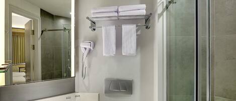 A modern bathroom with a glass shower enclosure, a white sink with a mirror, and a towel rack with folded towels.