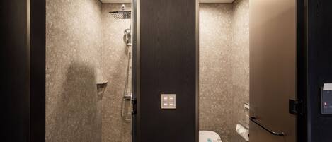 A modern bathroom with a shower, toilet, and a control panel on the wall.
