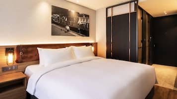 A hotel room with a large bed, a nightstand with a lamp, a wardrobe, and a wall-mounted picture.