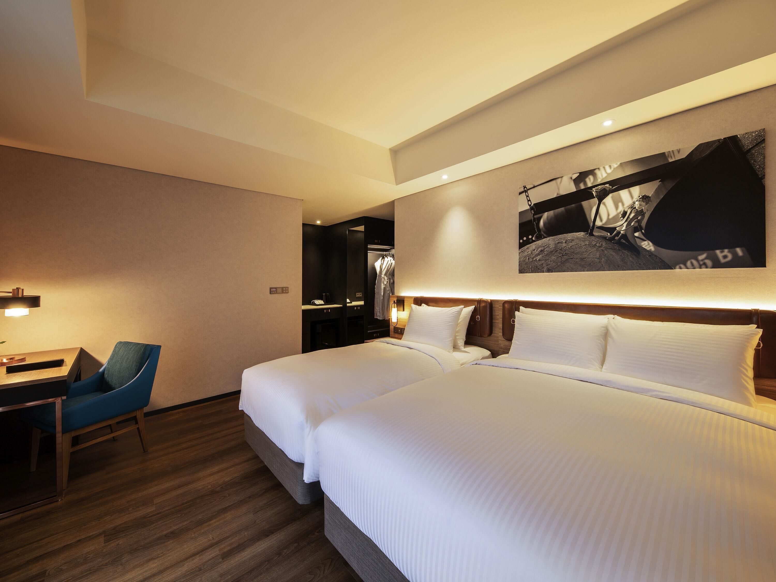 A hotel room with a large bed, a desk, and a chair.