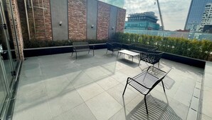 A rooftop terrace with outdoor seating, a glass wall, and a view of a cityscape. - Mercure Ambassador Seoul Hongdae (Seoul)