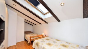 A compact bedroom with a skylight, two single beds, a small desk, and a wardrobe. - Beautiful sea View Apartment (Zadar)