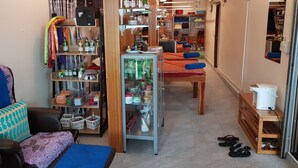 Ein kompakter, übersichtlicher Raum mit einem Bett, Regalen mit diversen Gegenständen, einem kleinen Tisch und einem Schrank.