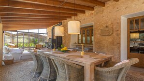 Un coin repas rustique avec une table en bois, des chaises en osier et un mur en pierre.