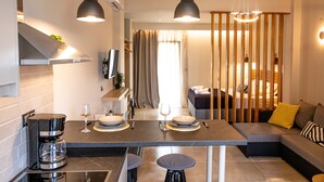 A modern kitchen with a dining area, a coffee machine, and a sofa with cushions. - Elysian Luxury Studio 4 (Roda, Corfu)