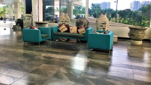 A lobby with teal chairs, large vases, and a tiled floor. - Angket Condominium Corner Apartment With Large Balcony (Pattaya)