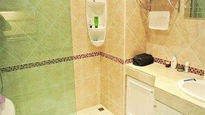 Un baño con ducha, lavamanos y espejo.