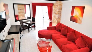 A modern living room with a red sofa, a glass coffee table, and a dining area with a table and chairs.