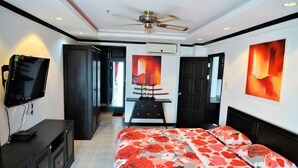 A modern bedroom with a large bed, a TV on a cabinet, and artwork on the walls.