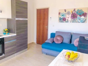 Relax in a cozy living area with a sofa, painting, and kitchenette.