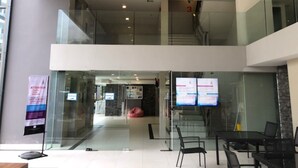 A modern hotel lobby with glass walls, a staircase, and a seating area with tables and chairs. - Laguna Beach 1A With Swimming Pool Views Pattaya (Pattaya)