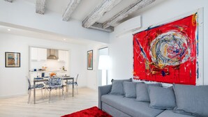 Un salon moderne avec un canapé gris, un tapis rouge et un grand tableau abstrait accroché au mur.
