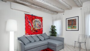 Un salon moderne avec un canapé d’angle gris, un tapis rouge et un grand tableau abstrait accroché au mur.