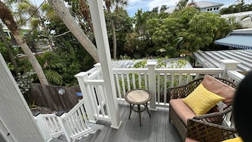 Relax on the covered deck surrounded by lush greenery and enjoy the serene atmosphere.