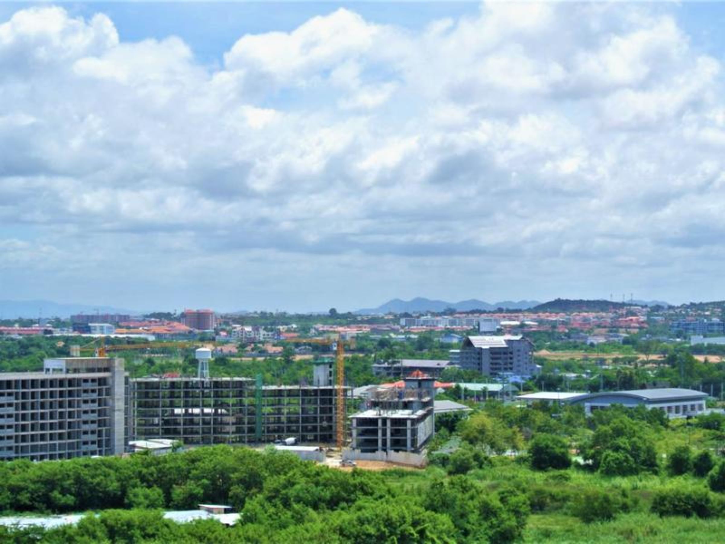A cityscape with various buildings, including a large multi-story structure and a smaller building under construction.