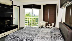 Una camera da letto con un letto, una TV, una scrivania e un balcone con vista.