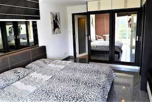 Une chambre à coucher comprenant un lit, une armoire et une porte-fenêtre coulissante donnant sur un balcon.
