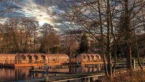 A row of wooden boats with arched roofs docked at a riverside pier.