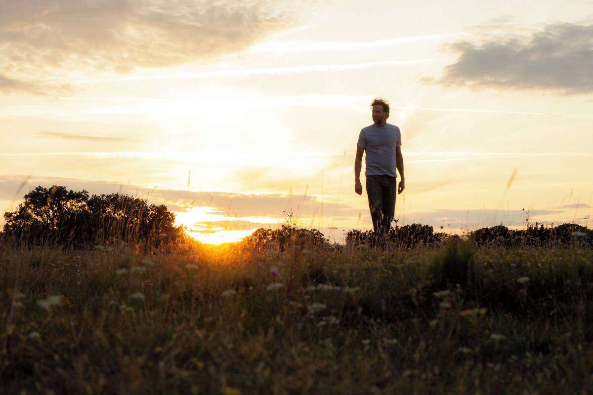 A person walking in a field during sunset.
